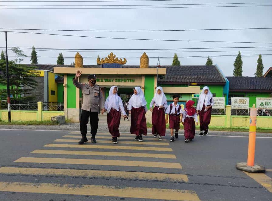 Polisi Membantu Menyeberangkan Anak Sekolah